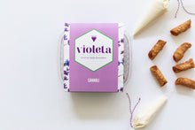 Load image into Gallery viewer, Lavender box of gluten free cannoli shells, surrounded by six cannoli shells and two piping bags of filling, tied with purple and white baker&#39;s string.